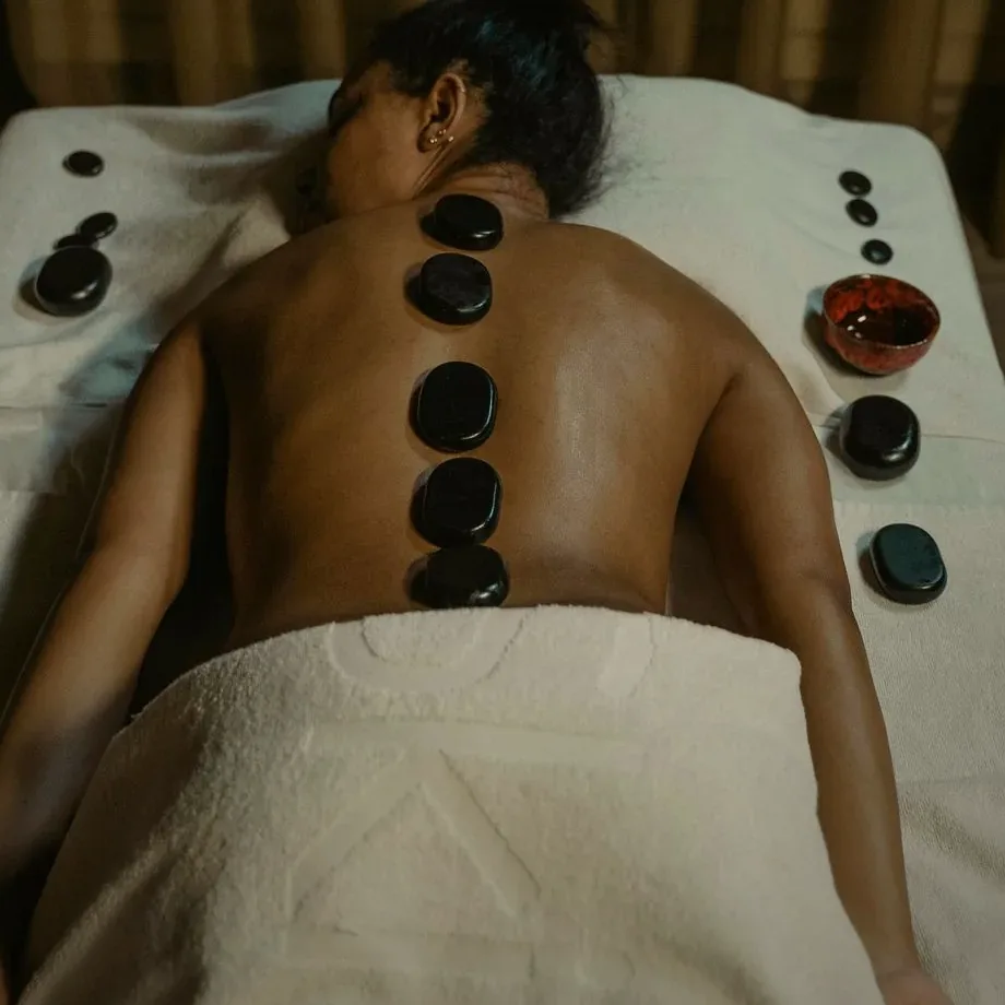 Massage du dos aux pierres chaudes : galets de basalte alignés le long de la colonne, serviette moelleuse